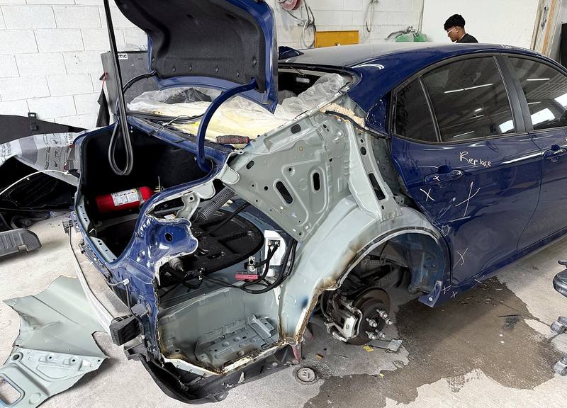 Sedan with outer panels removed showing damaged inner structure exposed for repair