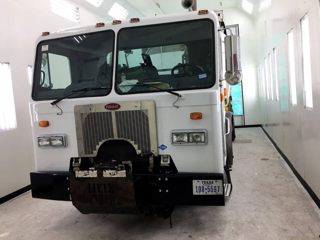 Heavy-duty commercial truck cab inside an oversized paint booth
