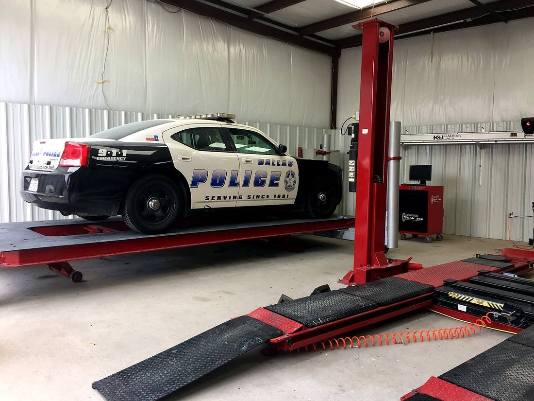 Police vehicle raised on a frame alignment rack inside the repair facility
