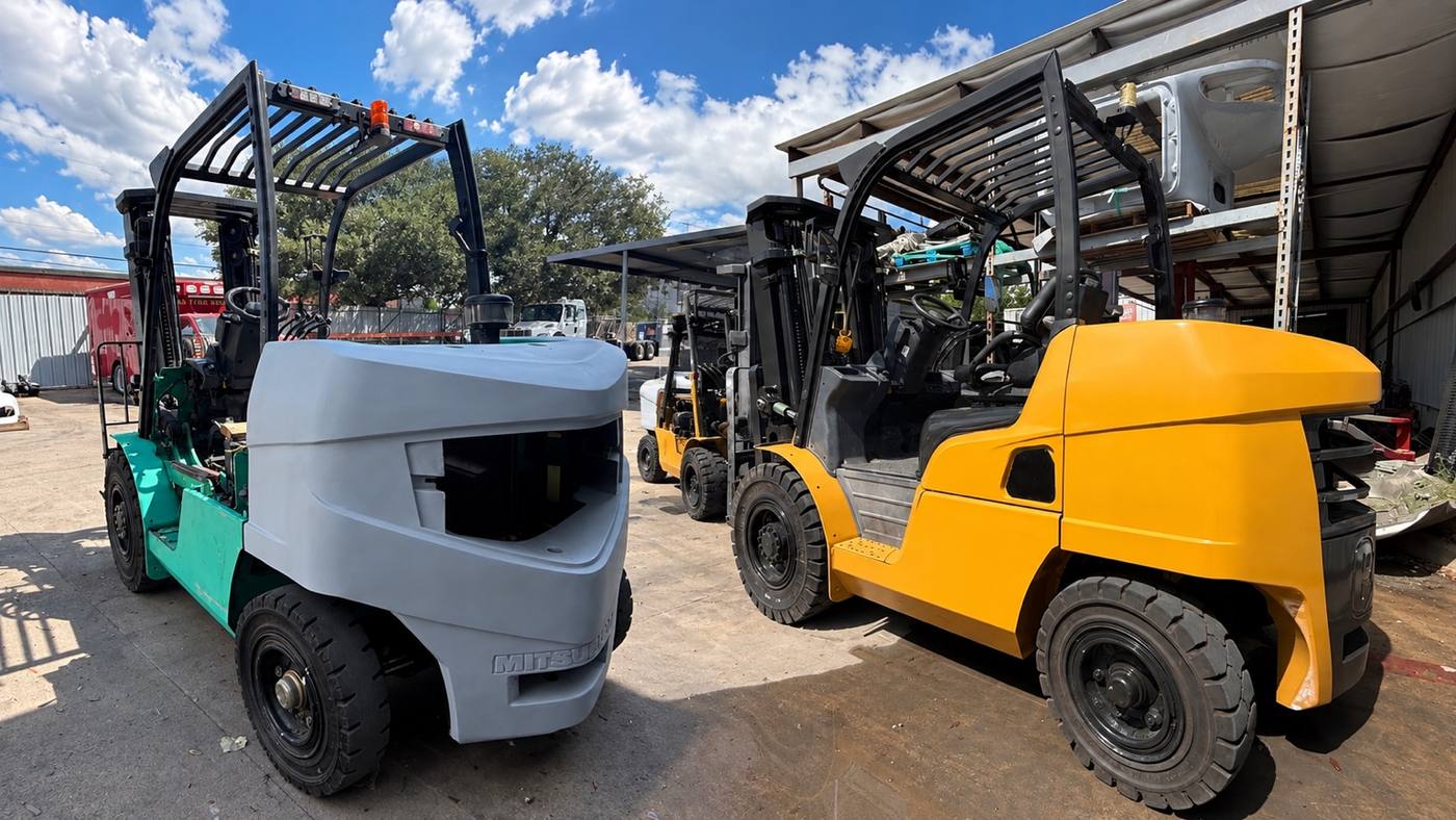 Two forklifts at the First Class Auto yard, one in primer and one refinished in yellow