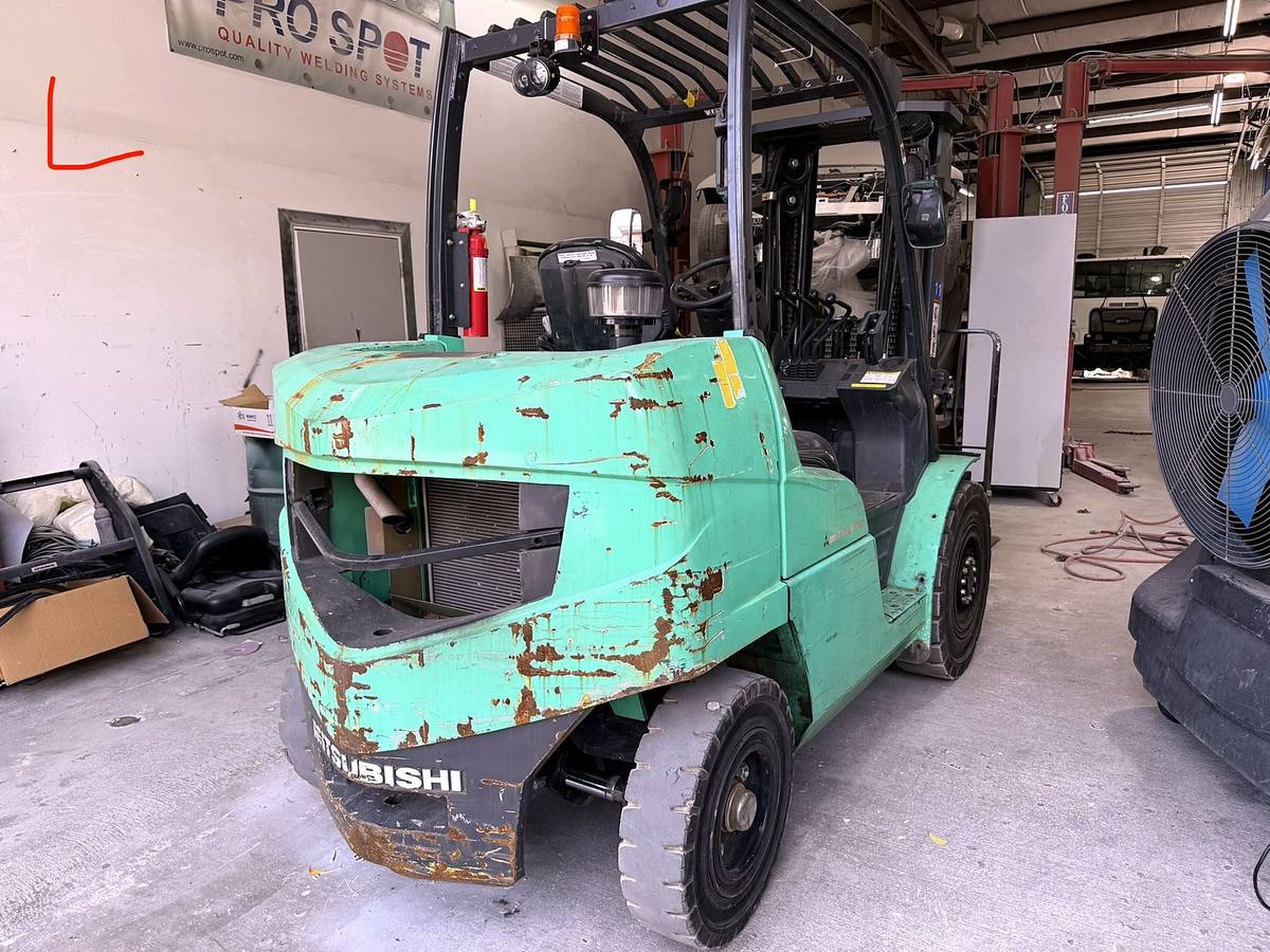 Industrial forklift on arrival, faded green paint with heavy surface rust and corrosion