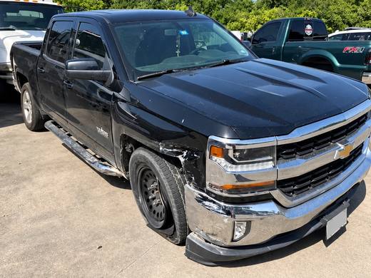 The same Silverado on arrival, with front-left impact damage to the fender, bumper and wheel