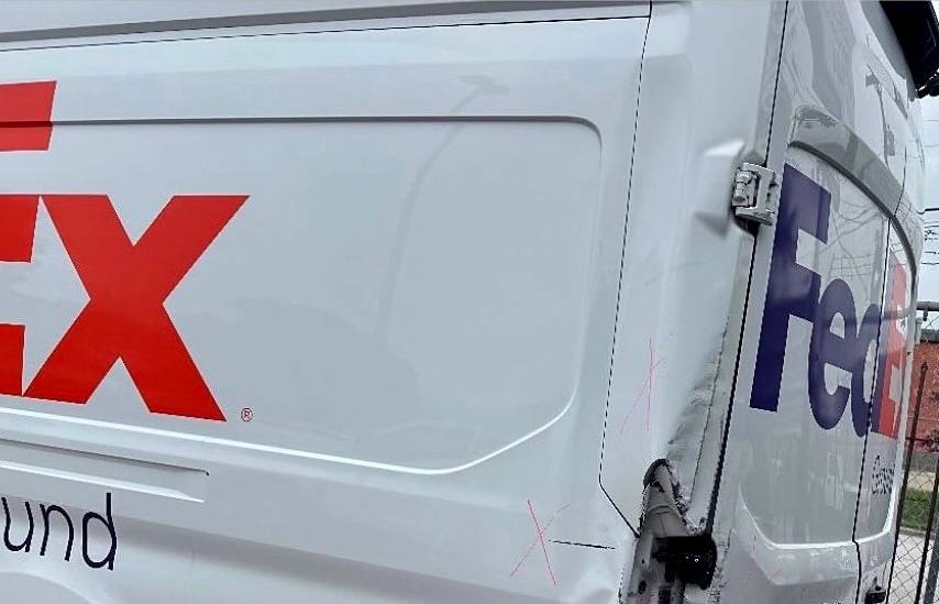 Commercial delivery van with impact damage along the rear body panel and door frame, marked up for repair